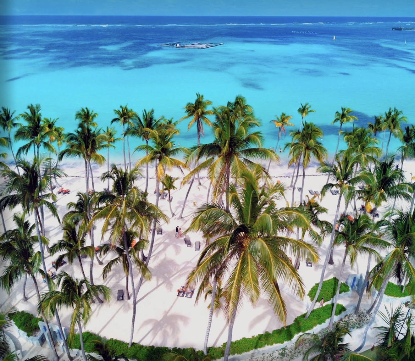 Vista aérea das praias de Punta Cana, com coqueiros, areia branca, mar turquesa e barcos no horizonte