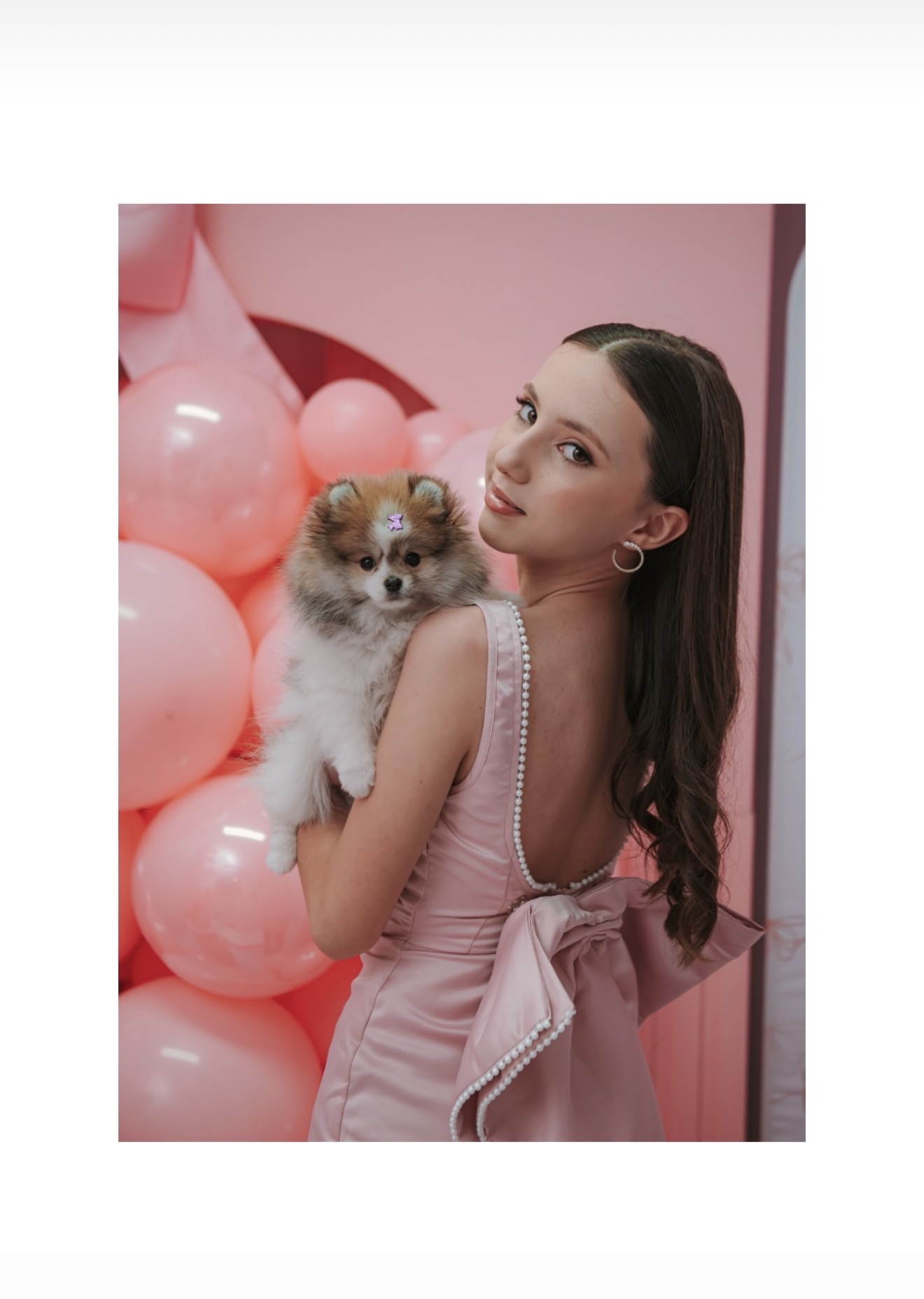 Jovem com cachorro e balões cor-de-rosa