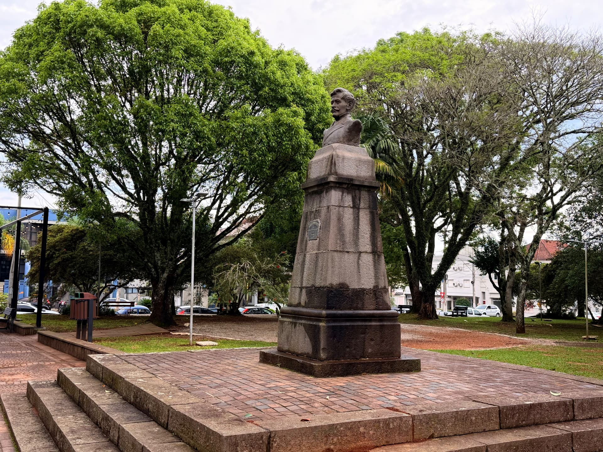Monumento com busto de Vespasiano Rodrigues Corrêa sobre pedestal de pedra, cercado pelas árvores da Praça Vespasiano Corrêa