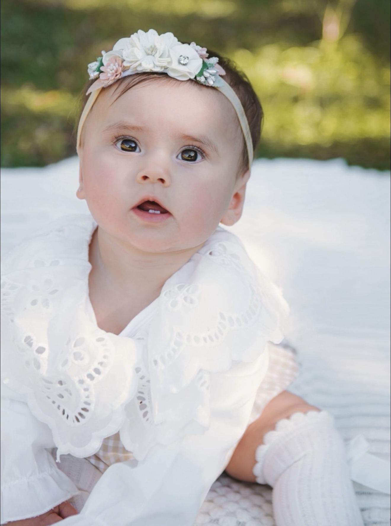 Bebê com roupa branca e tiara de flores