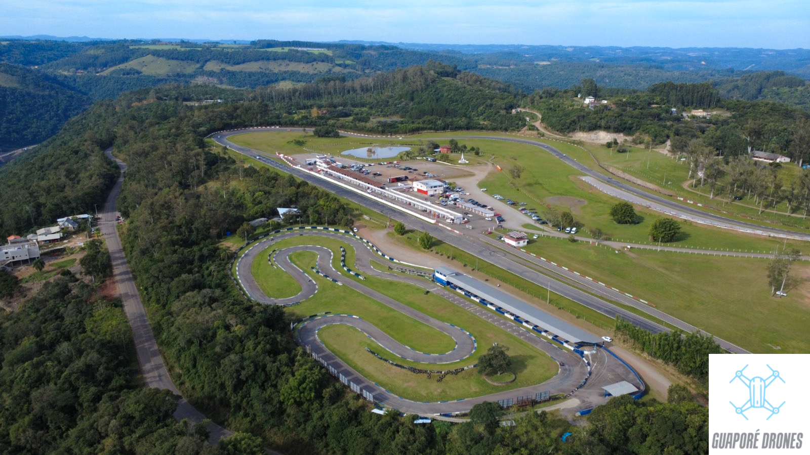 Vista aérea do kartódromo e da reta principal do autódromo de Guaporé, com boxes e veículos de apoio