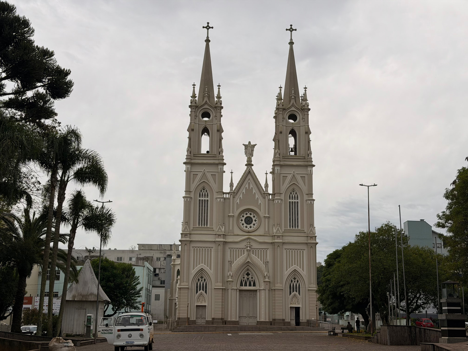 Fachada frontal da Igreja Matriz Santo Antônio vista da praça, com árvores e céu nublado