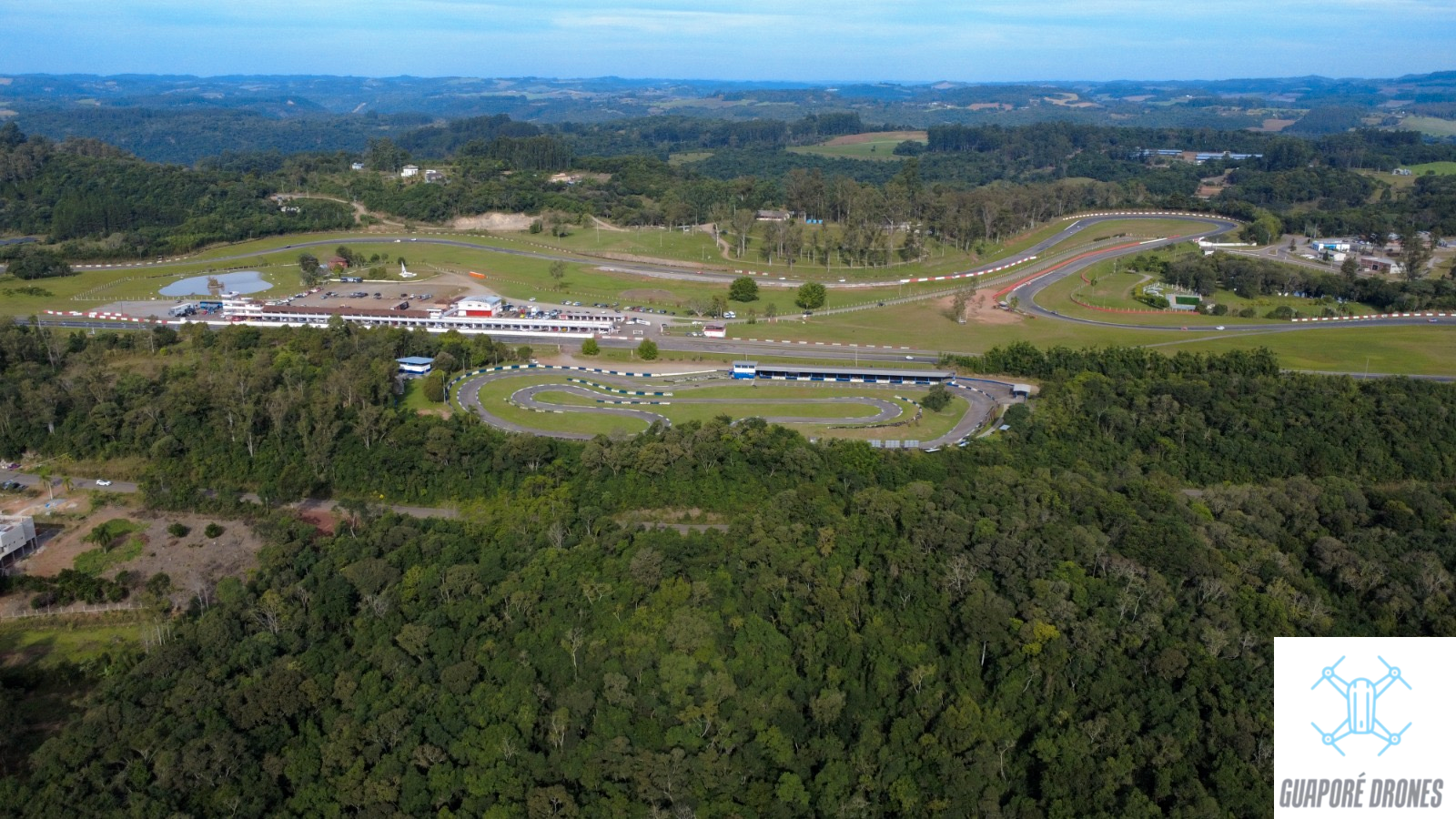 Panorâmica aérea do autódromo e do kartódromo de Guaporé cercados por mata e morros