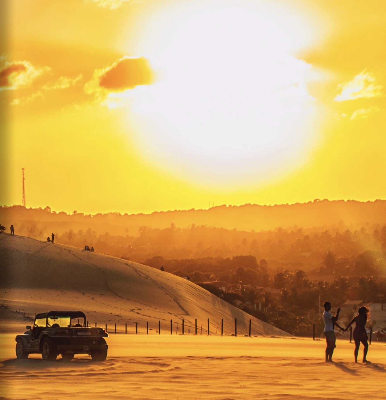 Natal: buggy e visitantes nas dunas sob um pôr do sol dourado