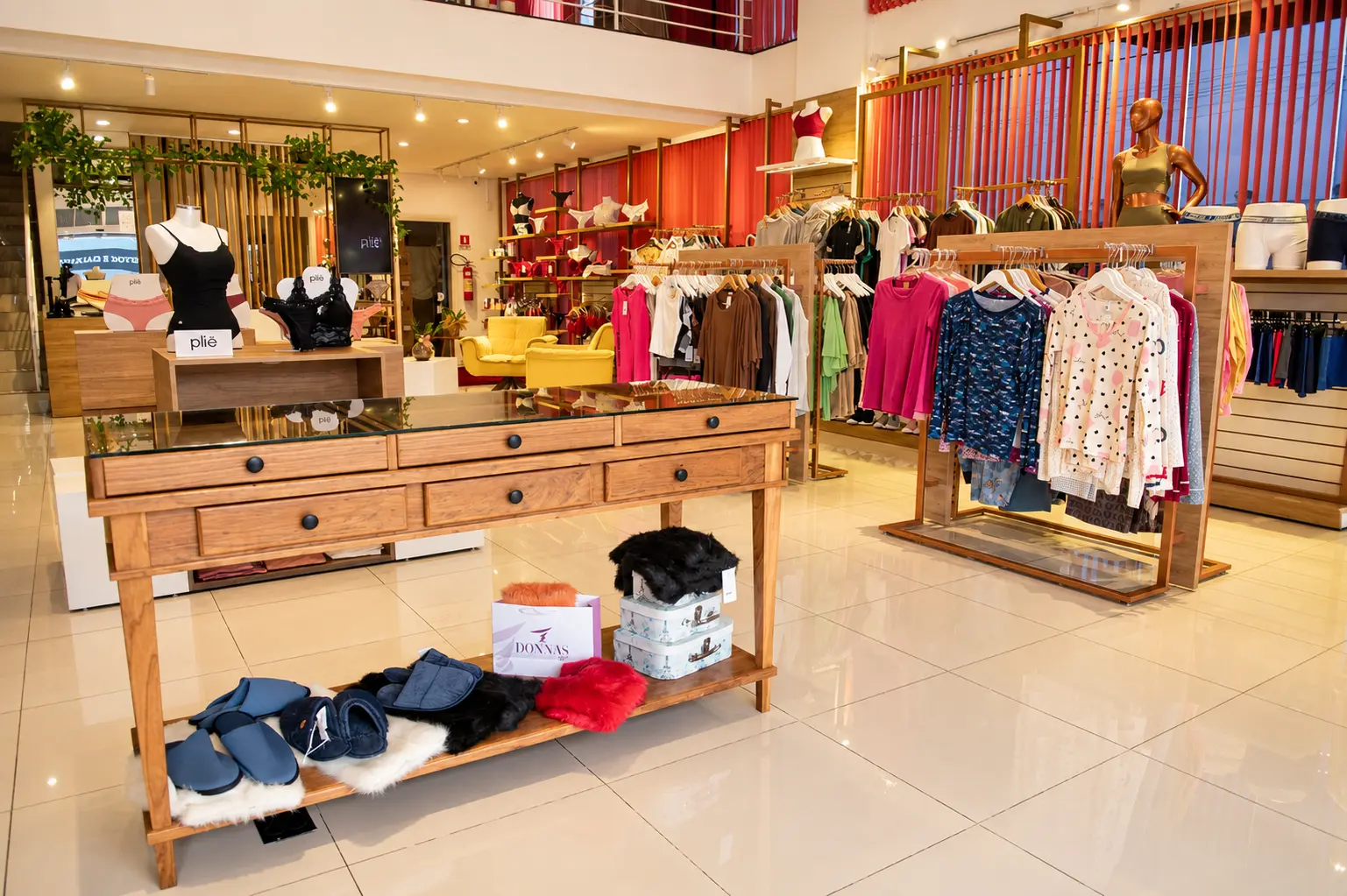 Interior amplo da loja Donnas de Si com mesas de exposição e roupas