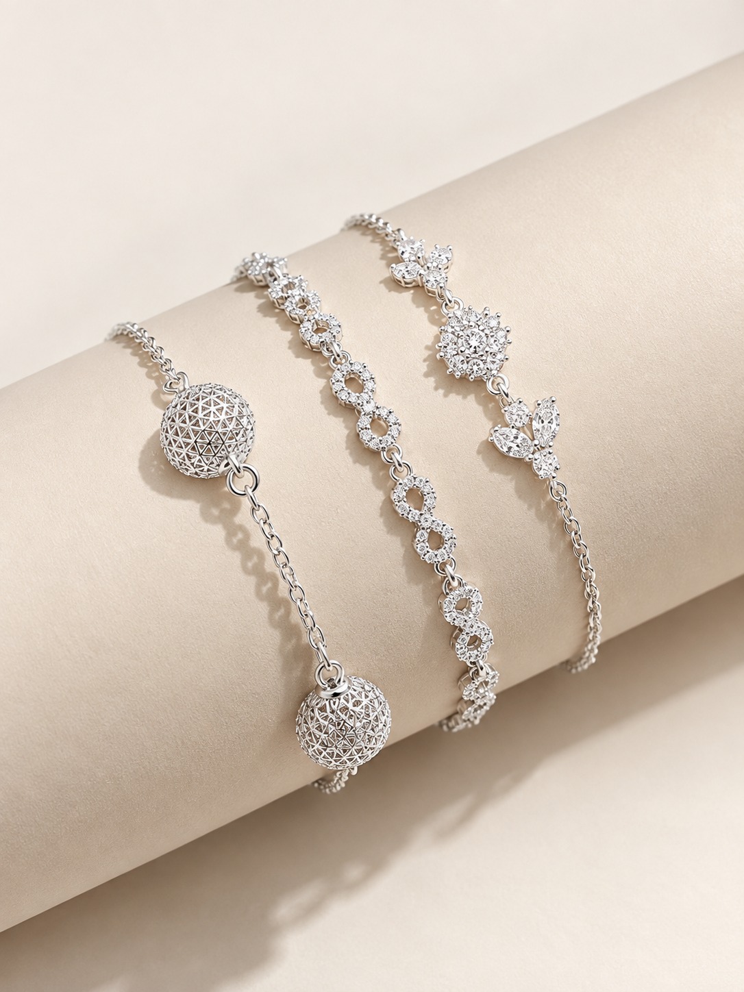 Três pulseiras prateadas cravejadas da Sol Jóias sobre base clara