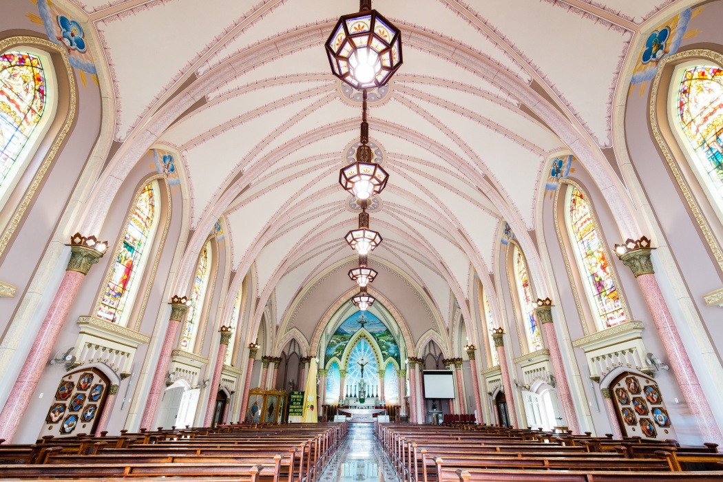 Nave da Igreja Matriz com bancos de madeira, vitrais e altar ao fundo